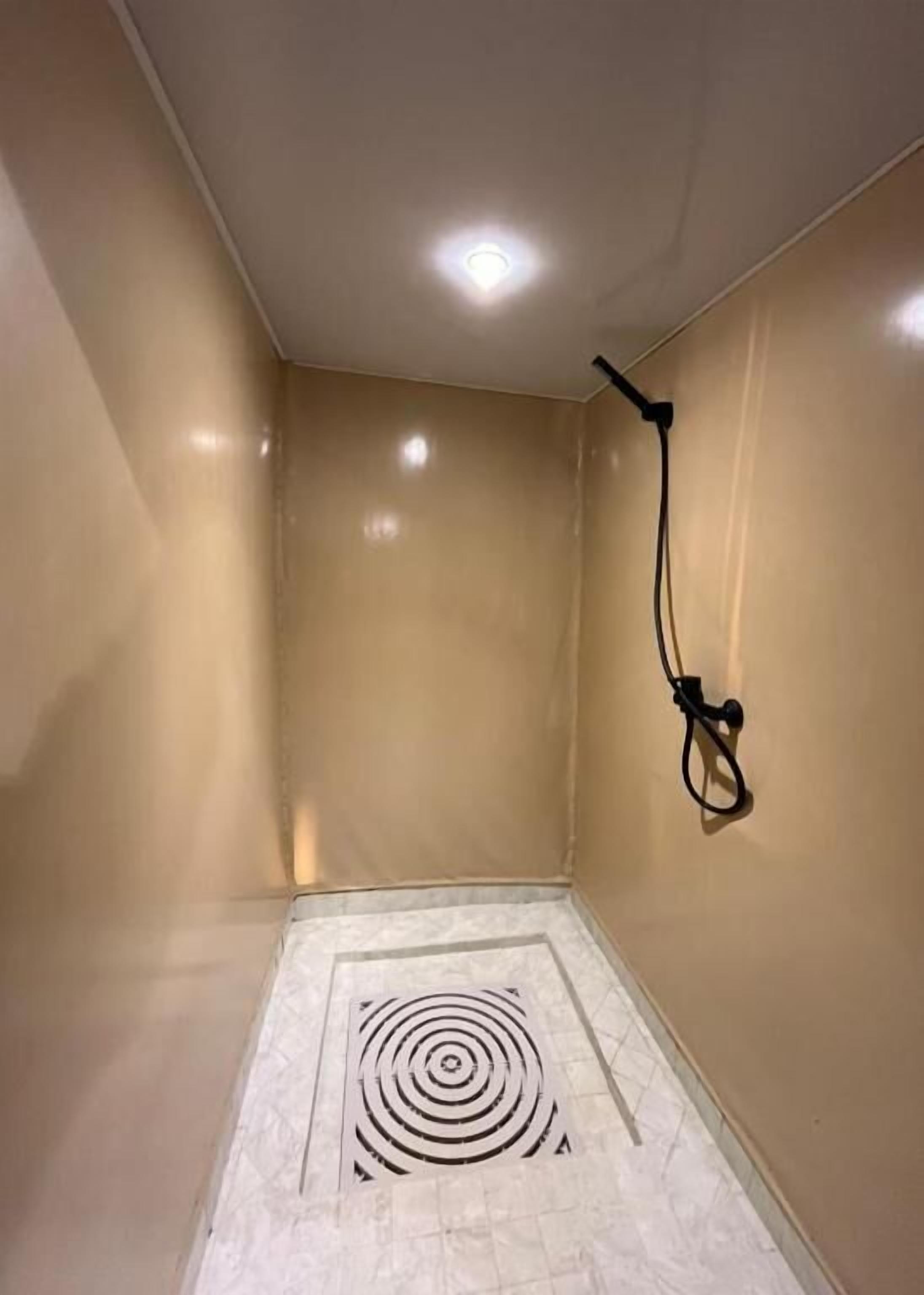 A bathroom with a shower, a tiled floor, and a ceiling light.