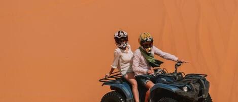Two people on an ATV in a desert setting.