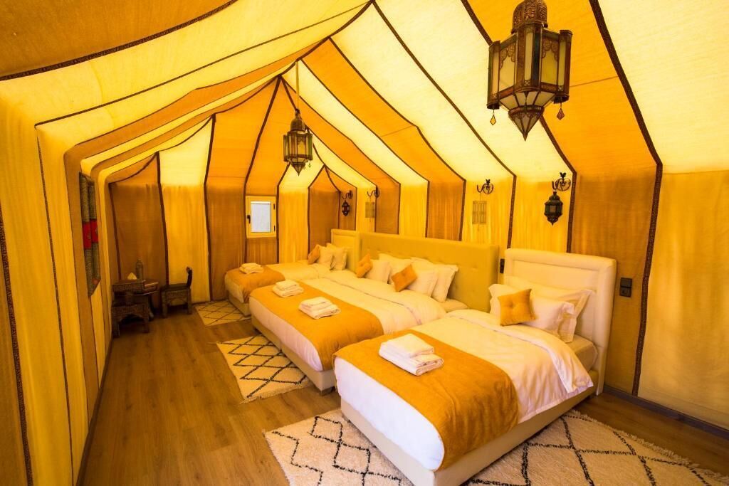 Una habitación acogedora de techo triangular con dos camas, una mesita pequeña y un farol colgante.