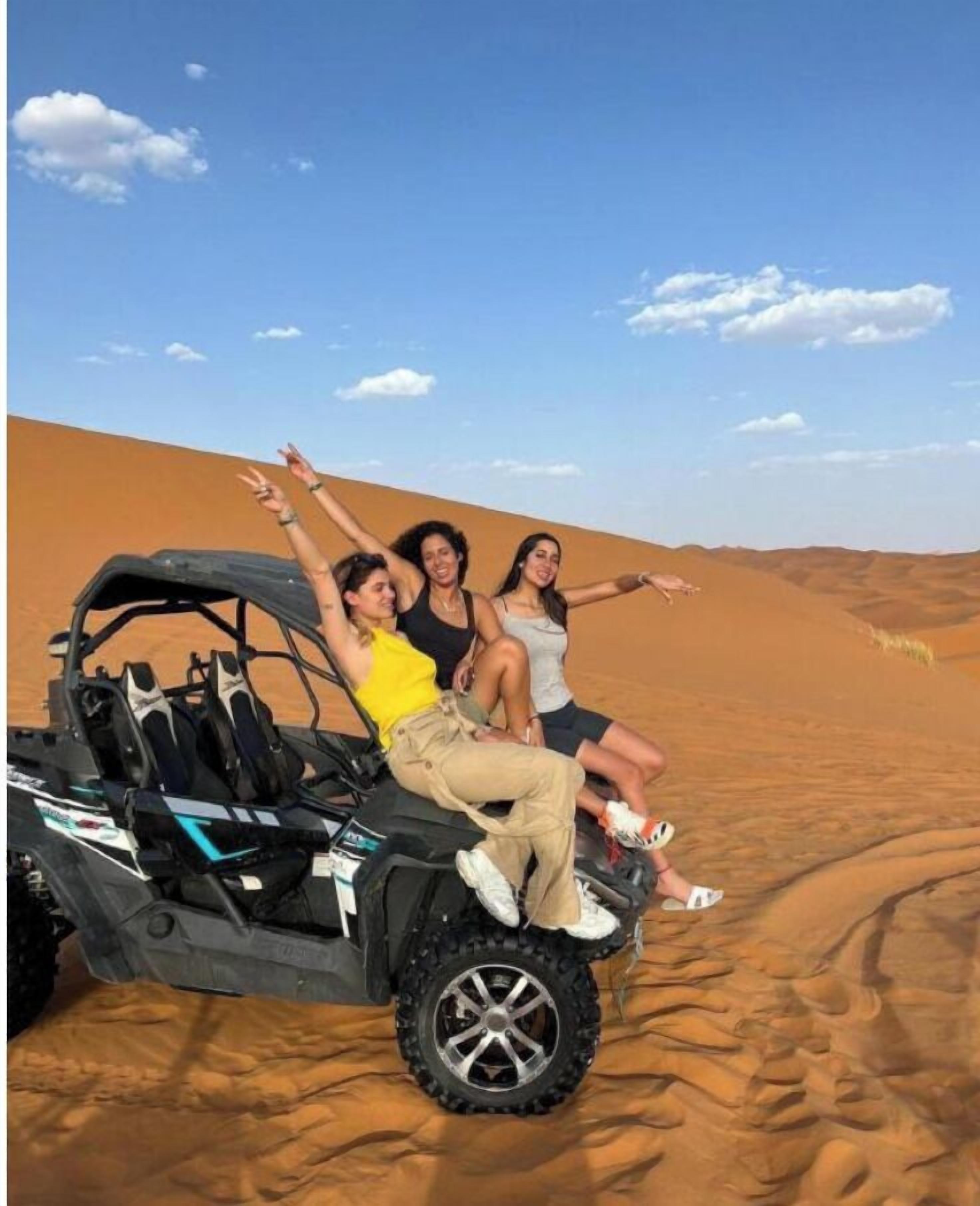 A group of people on a dune buggy in a desert landscape.