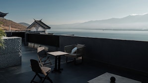 A terrace with a table and chairs, overlooking a calm lake and distant mountains. - Yunnan Hills&Harmony Retreat Dali Erhai (Dali)