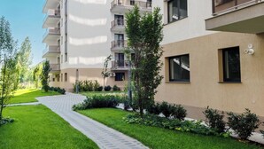 Een modern appartementencomplex met meerdere balkons, een geplaveid pad en groen beplantingsgebied.