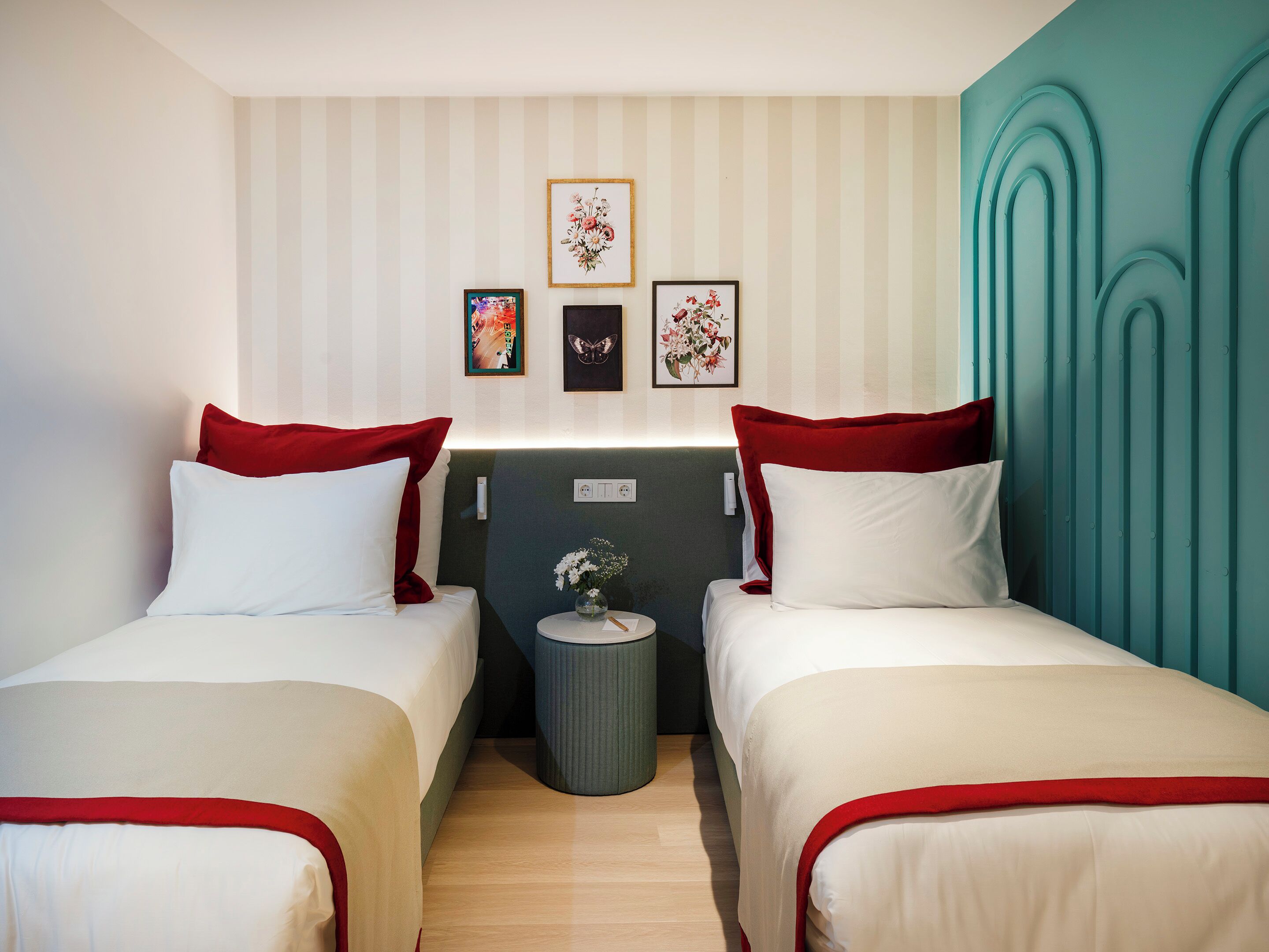 A hotel room with two beds, striped wallpaper, and a teal accent wall.