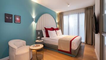 A hotel room with a bed, a chair, a small table, and a TV.