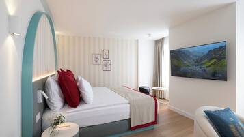 Una habitación de hotel moderna con una cama, una mesita con un florero, una silla y un televisor en la pared.