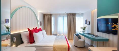 Een moderne hotelkamer met een groot bed, een bureau, een televisie en een badkamer.