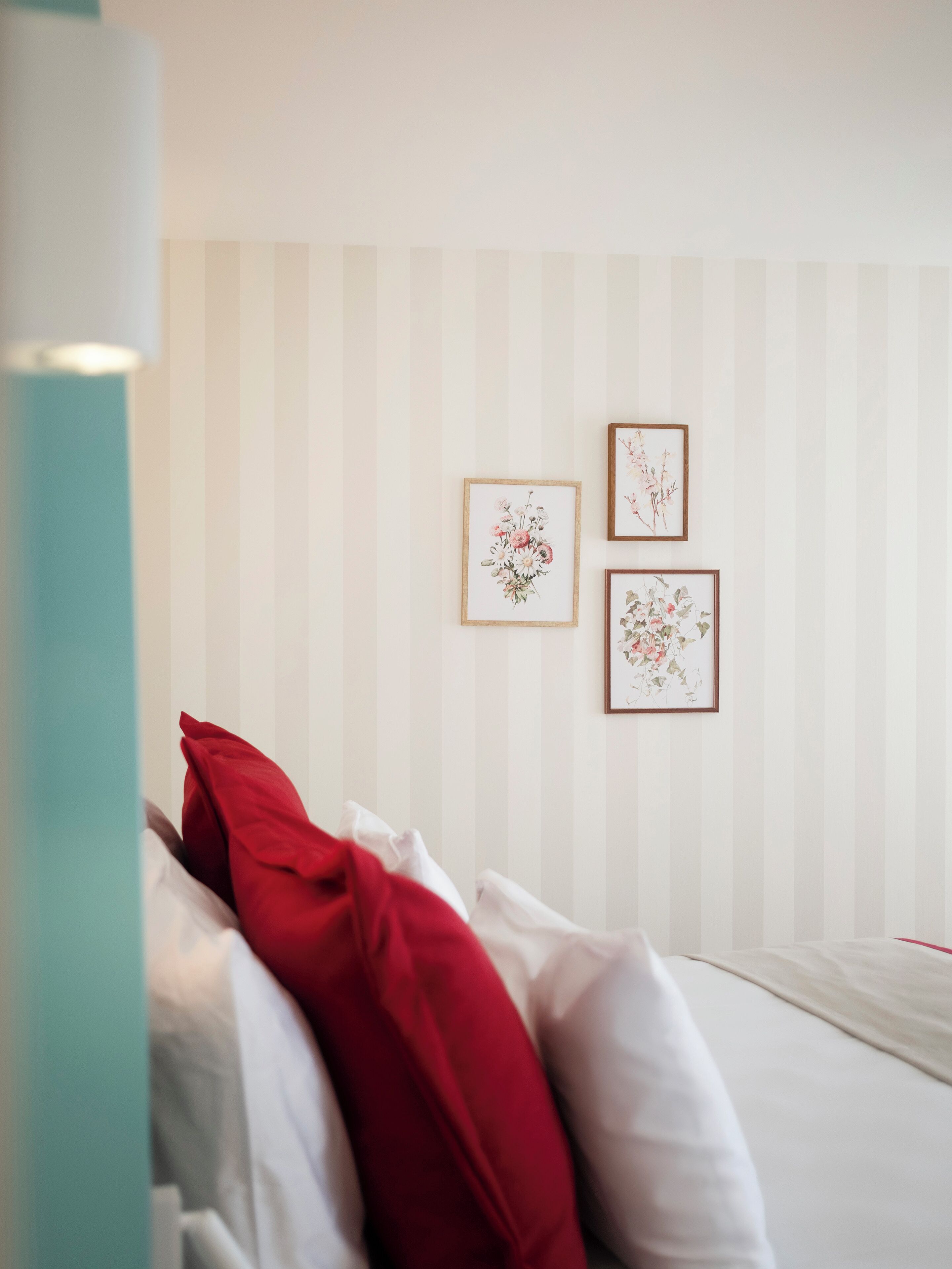 Ein Schlafzimmer mit einem Bett, Kissen und zwei gerahmten floralen Kunstwerken an der Wand.