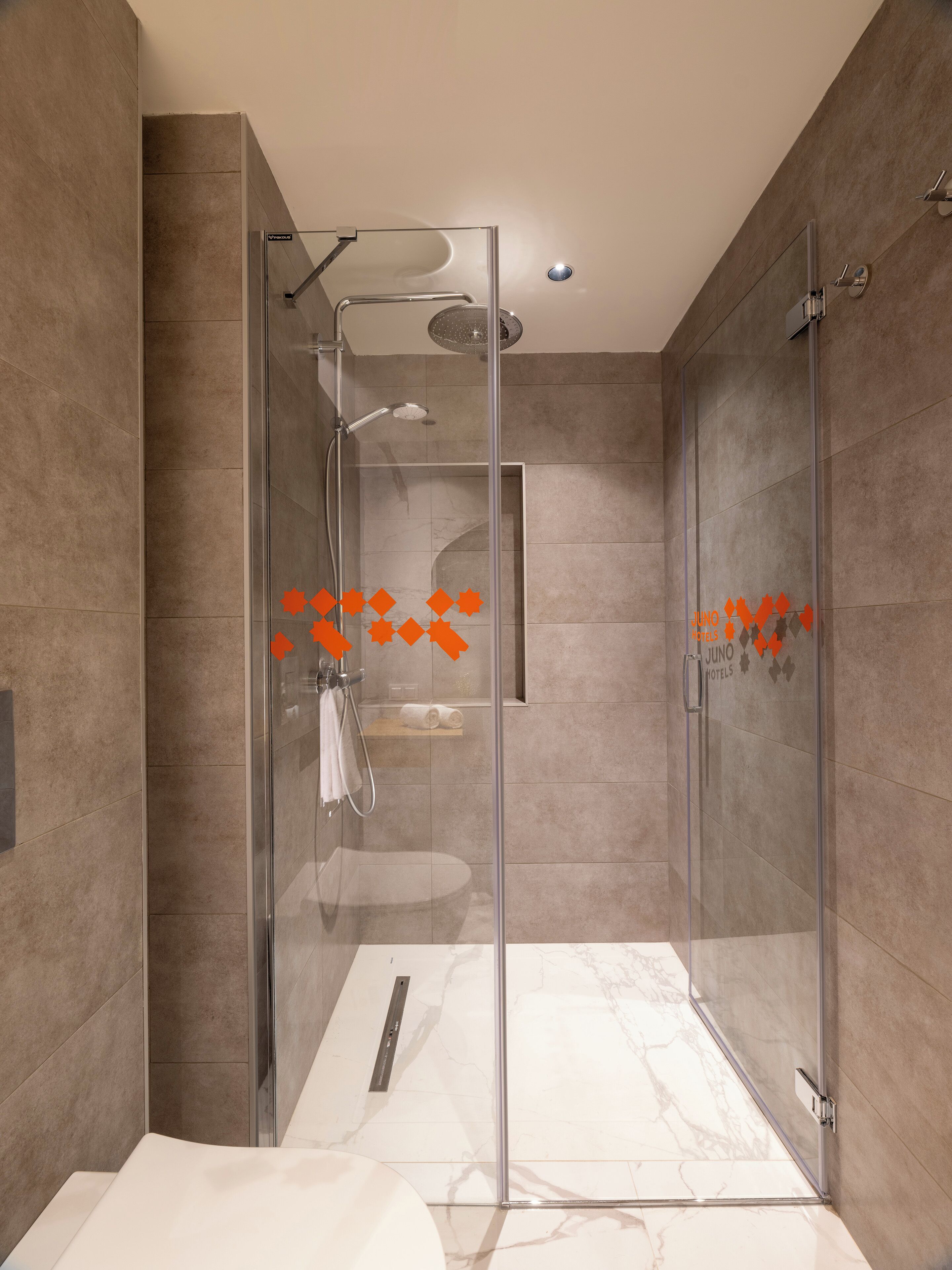 Ein modernes Badezimmer mit einer gläsernen Duschkabine, Marmorböden und einem sichtbaren Handtuchhalter.
