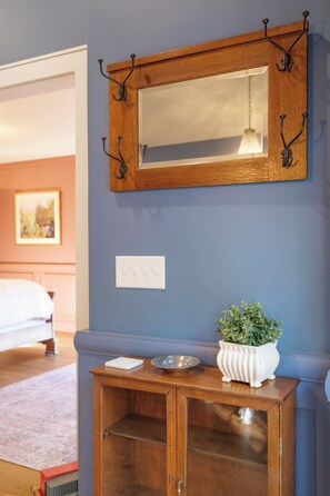 Um quarto com uma mesa consola de madeira, um espelho e um vaso de planta.
