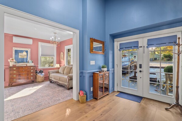 A room with a wooden floor, a beige sofa, a wooden cabinet, and a mirror on the wall.