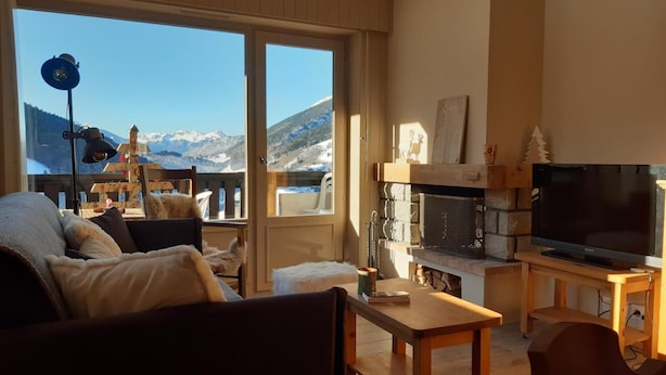 A cozy living room with a large window offering a mountain view, a fireplace, and a television. - Wifi, 1st floor, balcony, parking, tv, ski locker, 44m², Le Grand Bornand (Le Grand-Bornand)