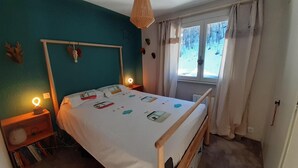 A bedroom with a bed, bedside tables, a window with curtains, and a view of trees outside.