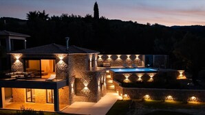 Ein modernes Haus mit Natursteinaußenwand, einem Swimmingpool und Sitzmöglichkeiten im Freien.