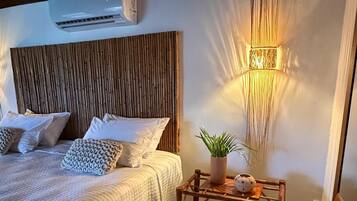 A bedroom with a bed, bedside table with a plant, and a wall-mounted lamp.