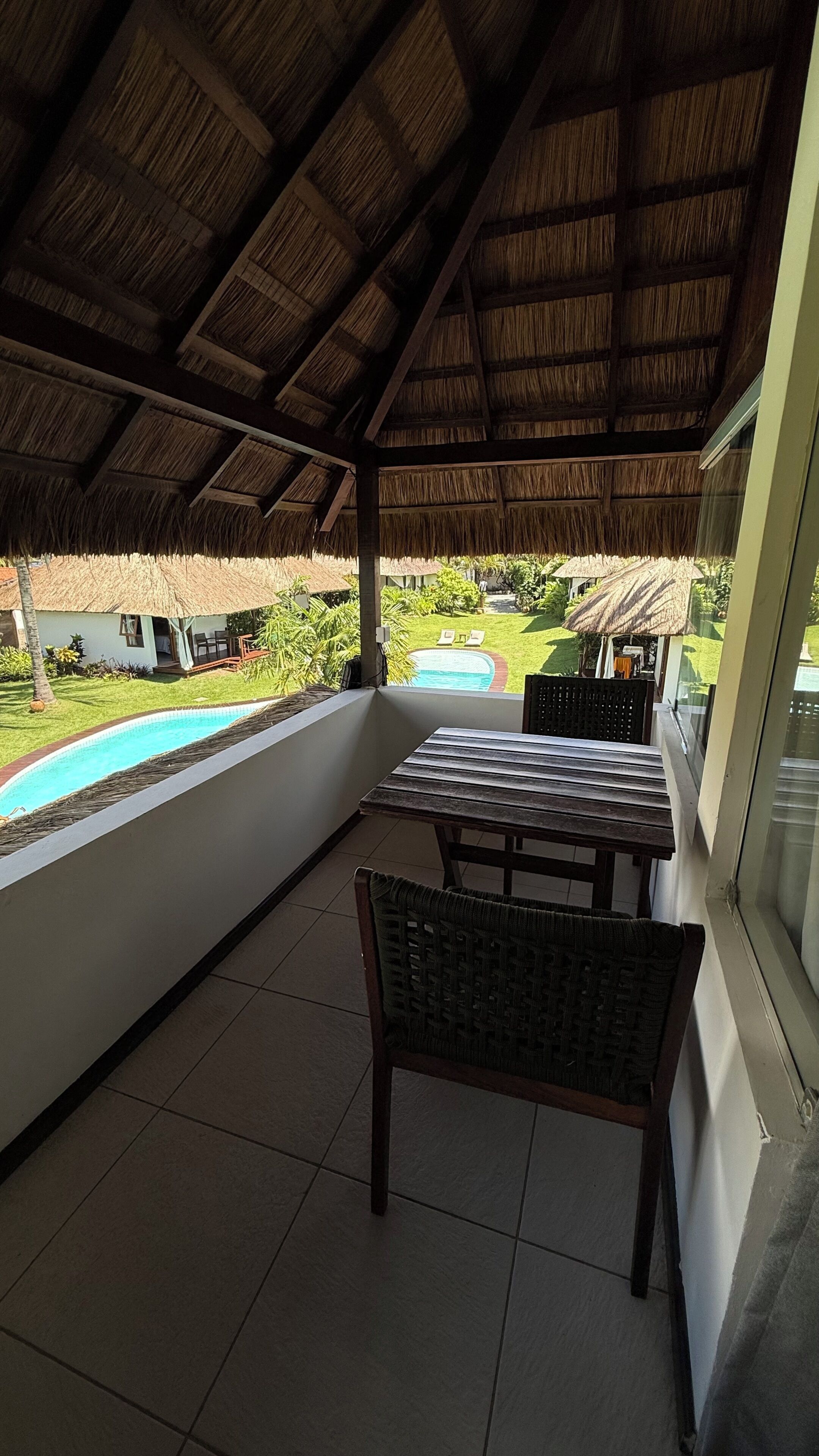 Une terrasse couverte avec une piscine, une table et des chaises.