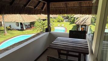 Une terrasse couverte avec une piscine, une table et des chaises.