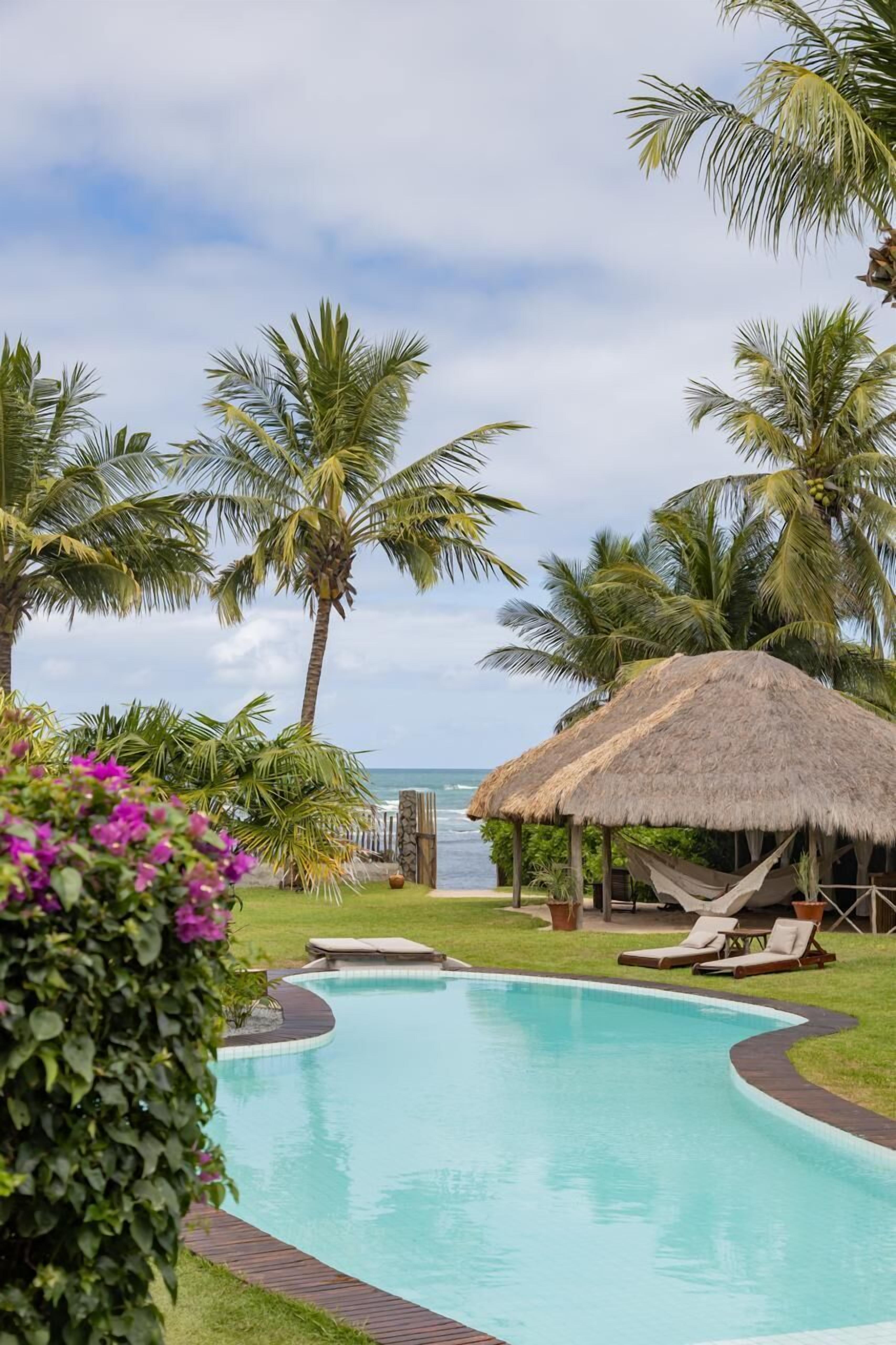 Na praia, areia branca, espreguiçadeiras, guarda-sóis 