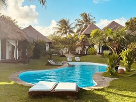 Una piscina al aire libre, sombrillas, sillones reclinables de piscina