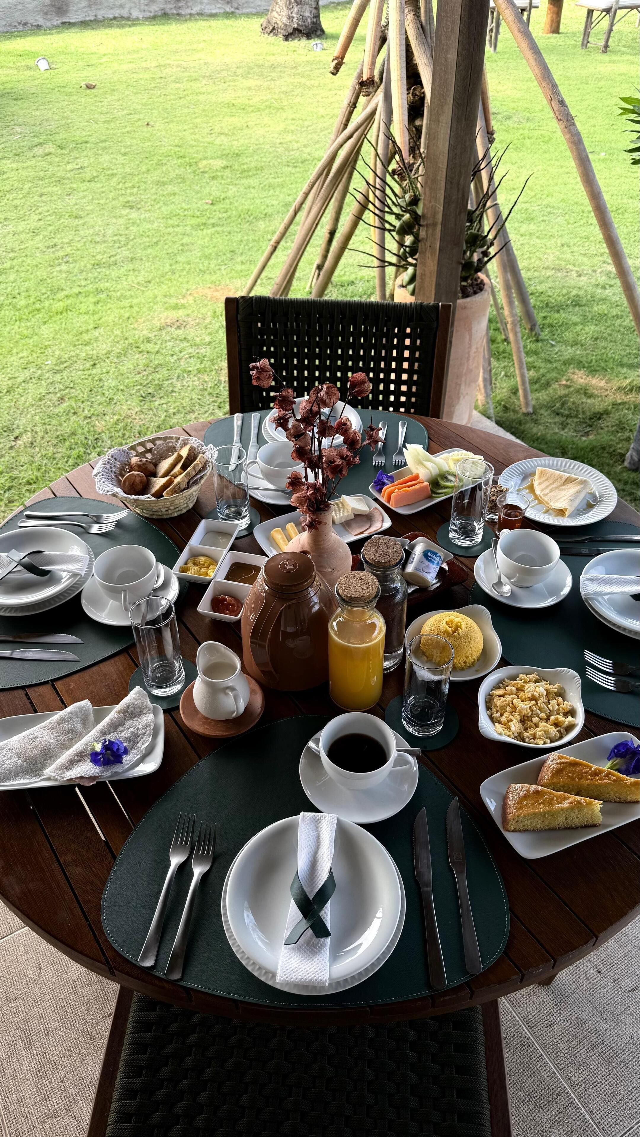 A round table set outdoors with various breakfast items, including eggs, toast, and beverages.