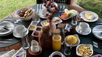 A round table set outdoors with various breakfast items, including eggs, toast, and beverages.