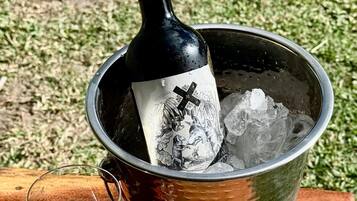 Una botella de vino en un balde de metal con hielo, una copa de vino y una superficie de madera.