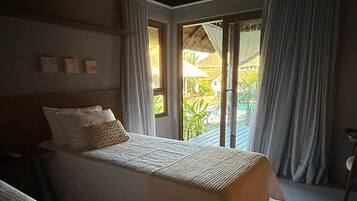 Une chambre avec deux lits, un plafond en bois et une vue sur un jardin grâce à de grandes fenêtres.