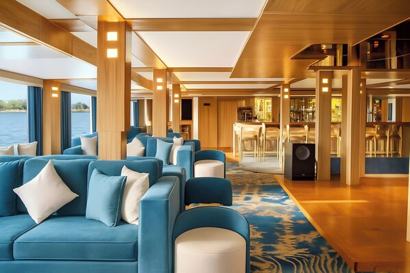 A modern interior with a blue sofa set, wooden accents, and a view of the water.
