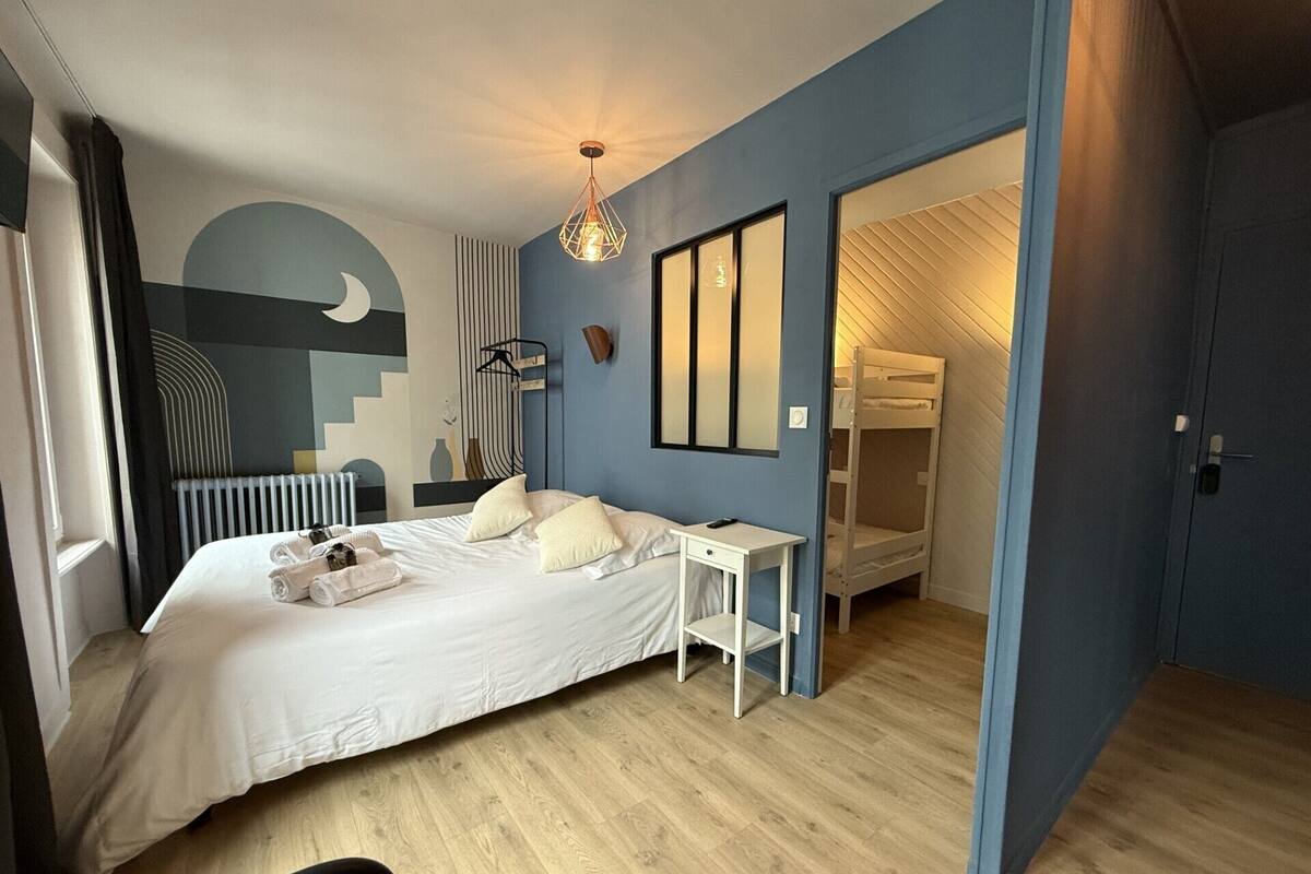 A modern bedroom with a large bed, bedside table, and a bunk bed in the corner.