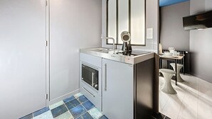 A compact kitchen with a built-in oven, a sink, and a mirror above it. - Appart Hôtel de la Baie  (Saint-Jean-le-Thomas)