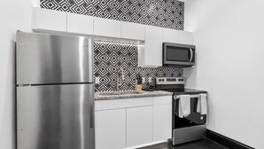 A modern kitchen with stainless steel appliances, a microwave, and patterned backsplash tiles. - Apartment 2: Okmulgee Main St (Okmulgee)