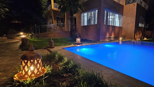 A swimming pool with a blue hue, surrounded by a paved area with decorative lanterns.