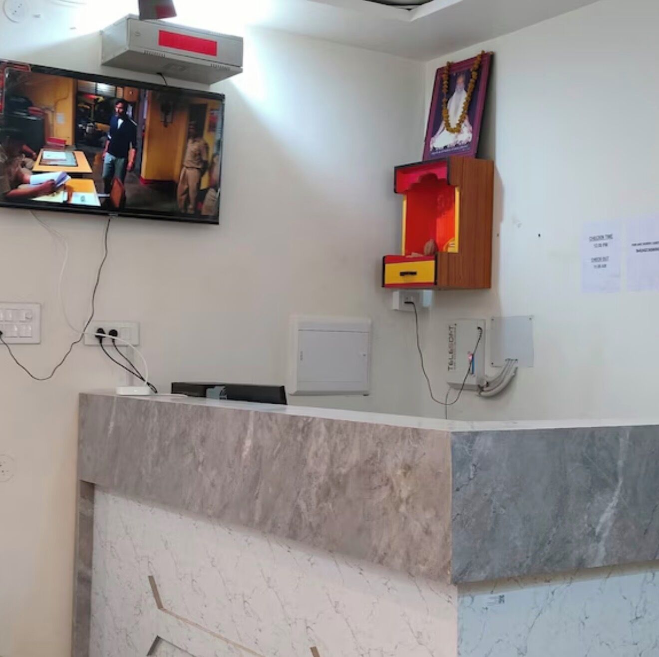 A reception desk with a television mounted above it, a telephone, and a wall-mounted electrical box.