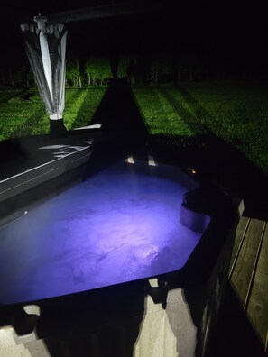 Ein Whirlpool mit dunklem Innenraum und einer umlaufenden Holzterrasse.