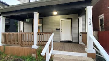 A residential porch with a wooden railing, a white door, and a mailbox.