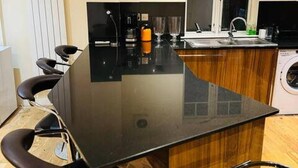 Cucina con piano di lavoro nero, lavatrice e lavandino.