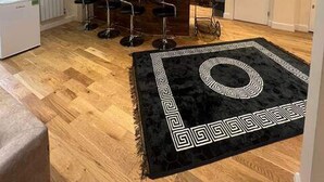 Una cucina moderna con isola centrale, sgabelli da bar e un tappeto nero a motivi geometrici.