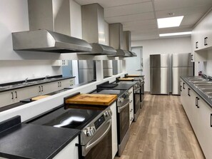 A modern kitchen with stainless steel appliances, a central island, and a wood countertop.