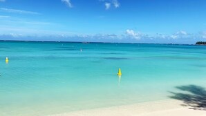 A beach with clear turquoise water, a sandy shore, and a few yellow buoys. - Exceptional apartment with a view of the golf course and beach—a 3-minute walk away (Grand Baie)
