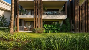A modern hotel with a two-story structure, balconies, and a well-maintained garden with tropical plants. - Exceptional apartment with a view of the golf course and beach—a 3-minute walk away (Grand Baie)