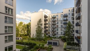 Een modern appartementencomplex met meerdere balkons, een centrale binnentuin met beplanting, en een heldere lucht.