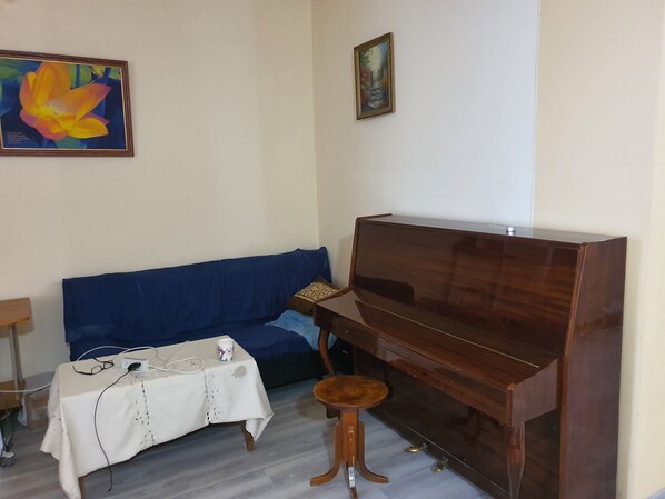 A living room with a dark wooden piano, a blue sofa, and a small wooden stool. - Armena - Nork Marash (Yerevan)