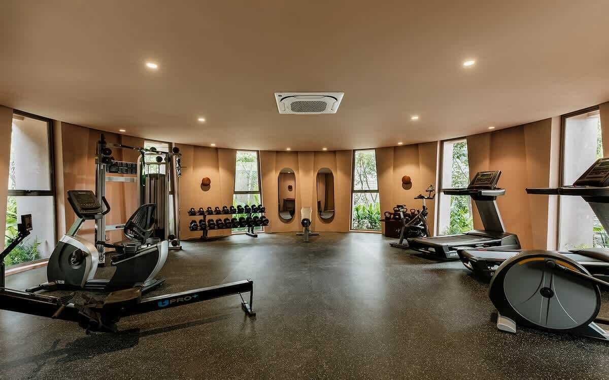Ein Fitnessstudio mit Cardiogeräten, Gewichten und Spiegeln.