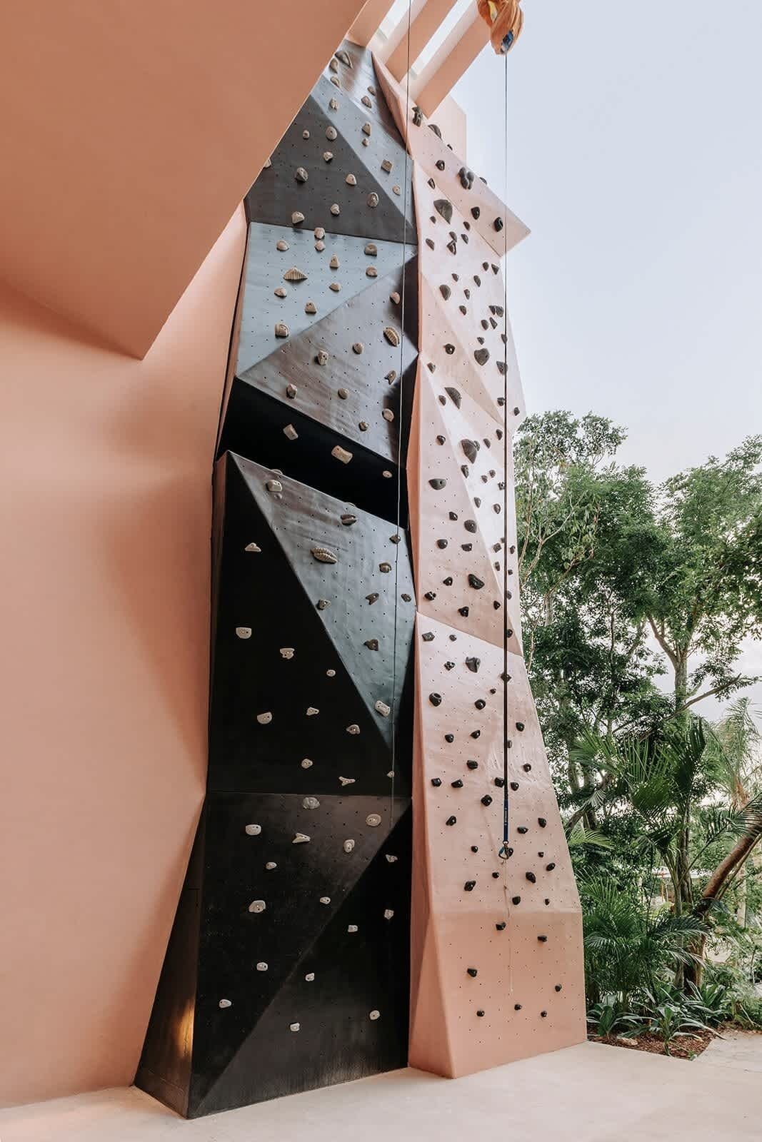 A climbing wall with various holds and a rope.