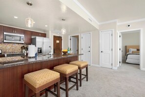 A modern kitchen with a central island, bar stools, stainless steel appliances, and pendant lighting. - Honua Kai | Ocean View 4 BR, Sleeps 14 | Car Incl. w/ 6+ Nights | HKK ML-1397 by KBM (Lahaina)