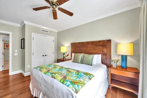A hotel room with a bed, wooden headboard, two bedside tables with lamps, a ceiling fan, and a door. - Honua Kai | Ocean View 5 BR, Sleeps 14 | Car Incl. w/ 6+ Nights | HKK ML-1403 by KBM (Lahaina)