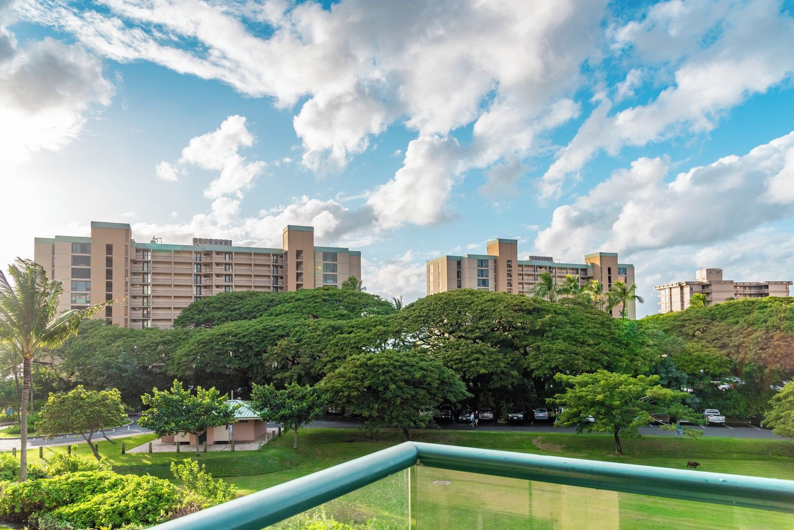 Complejo residencial con varios edificios de apartamentos, rodeado de exuberante vegetación y un cielo despejado.