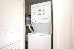 A compact laundry room with a front-loading washer and dryer, a control panel with operating instructions, and a visible vent hose. - Honua Kai | Ocean View 5 BR, Sleeps 14 | Car Incl. w/ 6+ Nights | HKK ML-1403 by KBM (Lahaina)