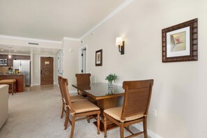 A dining area with a wooden table and chairs, a vase with flowers, and a framed picture on the wall. - Honua Kai | Ocean View 7 BR, Sleeps 22 | Car Incl. w/ 6+ Nights | HKK ML-1406 by KBM (Lahaina)
