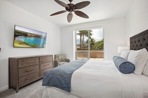Un dormitorio con cama, cómoda, ventilador de techo, una ventana grande con vistas y un cuadro en la pared.