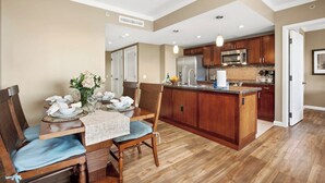 A modern kitchen with wooden cabinets, a central island, and a dining area with a table set for four.